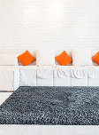 Dark gray rug with orange cushions on a white sofa